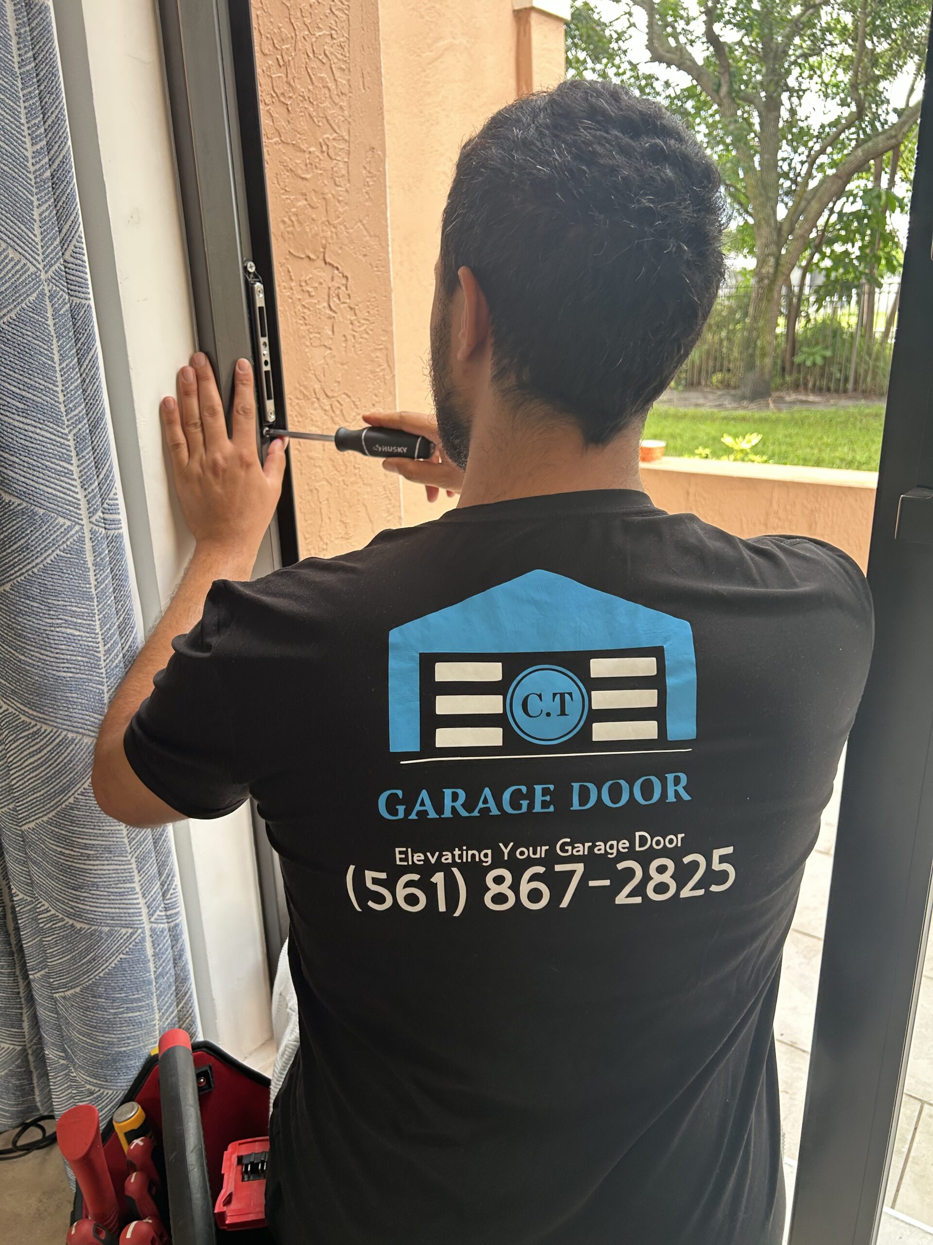 Technician servicing a sliding glass door frame in North Palm Beach, FL